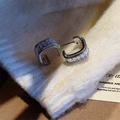 Macro shot of silver-colored C-shape earrings with baguette-cut zircon on white knit fabric - Silver - Zirconia Square