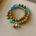 Makrodetail eines doppellagigen Perlenarmbands mit blauem Kürbis-Anhänger und Goldakzenten - Osmanthus Duft Doppelring Hulu