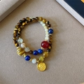 Detail of beaded bracelets with tiger eye stones, blue crystal, and a gold Buddha charm - 6mm Tiger Eye Blue Kyanite