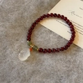 Detail of red garnet beaded bracelet with a white jade rabbit pendant on plush background - Garnet - Moon Rabbit
