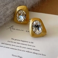 Dettaglio di orecchini vintage dorati con texture spazzolata e intarsio in zircone - Stile Zirconia Ovale Oro (E2962)