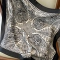 Dettaglio di un elegante foulard in seta paisley bianco e nero con finitura satinata su sedia - Naturale Con Bordo Nero