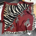 Detailed close-up of burgundy zebra print silk scarf with luxury smooth satin texture - Red