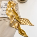 Détail d'un foulard en soie à damier jaune gingembre posé sur un costume beige chic - 100cmx8cm / Damier Jaune