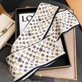 Eleganter Seidenschal mit Blumenmuster als dekoratives Band an einer beigen Handtasche - Beige-Schwarz