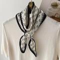 Elegant black and white pleated scarf with geometric print on a white knit sweater - Beige
