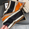 Detalle de un pañuelo largo de seda con patrón geométrico en un bolso de piel - Naranja Negro