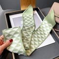 Close-up of light green silk scarf with geometric triangle pattern in a black tray - Beige and Green