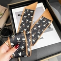 Détail d'un foulard étroit à motif floral élégamment disposé avec des accessoires - Noir