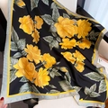 Primo piano di un foulard in seta con rose gialle stampate su tessuto di raso lucido - Nero