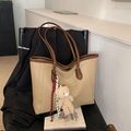 Borsa tote beige con manici marroni e ciondolo a orsetto su una sedia nera in pelle - Cachi Con Pendente