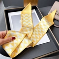 Yellow and white geometric triangle silk twilly scarf tied on a beige handbag handle - Beige