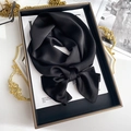 Detailed close-up of a black silk scarf tied in a bow on a luxury fashion book - 15*150cm / Black
