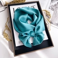 Detail of luxury solid cyan silk scarf tied in a bow on a stylish vintage tray display - 15*150cm / Lake Blue