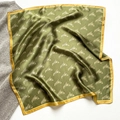 Flat lay of an olive green silk scarf featuring golden harp prints and yellow borders - 53*53cm / Dark Green (Harp Print)