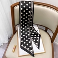 Dettaglio della sciarpa in seta a pois con bordi rosa drappeggiata su sedia morbida - Nero