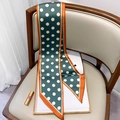 Dettaglio di un foulard in seta verde a pois drappeggiato su una sedia con rivista e rossetto - Blu Pavone