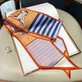 Dettaglio di un foulard in seta double-face con stampe di cavalli e bordi arancioni - Cachi
