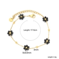 Détail d'un bracelet en acier inoxydable doré avec des breloques fleurs en perles noires - Style Fleur Noire Dorée (BR27260BG)