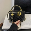 Schwarze gesteppte Tasche mit goldenem Metallgriff und Kettenriemen auf antikem Buch - Schwarz