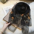 Elegant black sheer scarf with gold floral embroidery and metallic edges over a magazine - Gold Thread Embroidery Black