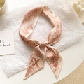 Détail d'un foulard Twilly beige avec motifs végétaux rouges et lettre X noué en nœud - Lettre X-Beige Rouge Brique