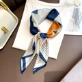 Dettaglio di un foulard in seta a motivi geometrici blu e arancio su t-shirt bianca - Azzurro