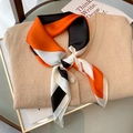Pañuelo de seda con bloques geométricos en naranja y negro sobre un suéter de punto - Naranja