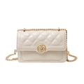 Quilted cream chain crossbody bag with gold floral clasp on a clean white background - White