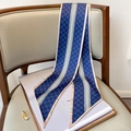 Dettaglio di foulard in seta blu navy con motivi dorati su una sedia grigia - Blu Con Bordo Cachi