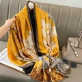 Detaillierte Nahaufnahme des goldenen Seidenschals mit Blumendruck auf grauem Sofa - 90*180cm / Ingwergelb