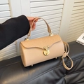 Elegant beige cylindrical box bag with pleated lid and gold clasp in hand-held pose - Khaki