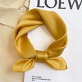 Close-up of a glossy yellow silk square scarf tied in a bow on a stylish beige polo shirt - 53*53cm / Ginger Yellow