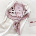 Detalle de un pañuelo de seda 100% con estampado floral morado atado a un vestido satinado - Estampado de diente de león / Rosa