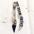 Dettaglio di un foulard Twilly bianco con motivo navy, testo Cherry Mood e spilla lusso - Nero