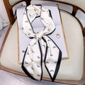 Elegant cream twilly silk scarf with black horse head print tied on a leather surface - White Horse Head