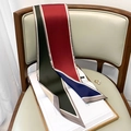 Close-up of a stylish geometric patchwork silk scarf draped elegantly over a wooden chair - Army Green Red