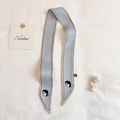 Dettaglio di sciarpa stretta in seta azzurra con elegante ritratto e scritta ok - Celeste