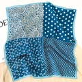 Détail d'un foulard carré en soie avec motifs cachemire bleus et pois en pliage doux - Bleu