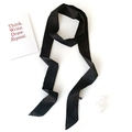 Detail of a sleek black satin skinny scarf and hair ribbon shown on a white minimal setup - Black