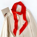 Detail of red silk ribbon tied on a beige shirt collar showing smooth texture and sheen - Red