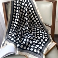Detailed view of polka dot silk scarf draped on leather chair showing glossy texture - 70x70cm / Polka Dot Black (W-176)