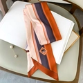 Détail d'un foulard en soie à rayures multicolores avec logo éléphant sur livre blanc - Bord Caramel