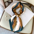Elegant striped skinny silk scarf in brown and green displayed on a magazine - Equestrian Badge Dark Blue Border (FX-103-Dark Blue Border)