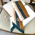 Détail d'un foulard en soie rayé avec logo éléphant et broche perle sur un magazine - Bordure Bleu Foncé
