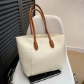 Minimalist cream white leather tote bag with brown handles on artistic chair - White