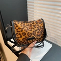 Retro leopard print shoulder bag with black strap and fashion patch on warm backdrop - Brown Leopard