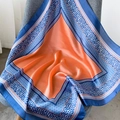 Sciarpa elegante in seta arancione con bordo leopardato su una sedia grigia - Arancione Blu