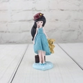 Detail of girl figurine with blue dress, brown suitcase and yellow bear on a round base - Blue B