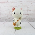 Close-up of a cute cartoon cat figurine with a brown bag on a green grass base - Large Backpack White Cat Ornament